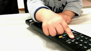 子どもがテレビのリモコンを触っている手元の写真