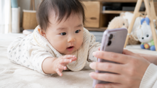 赤ちゃんがママのスマホに興味を持って手を伸ばしている様子