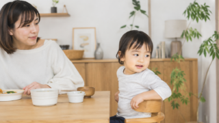 2〜3歳の子どもが食卓で後ろを振り返る様子と見守るママ