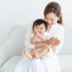 赤ちゃんを抱っこして笑顔で遊ぶお母さんの写真