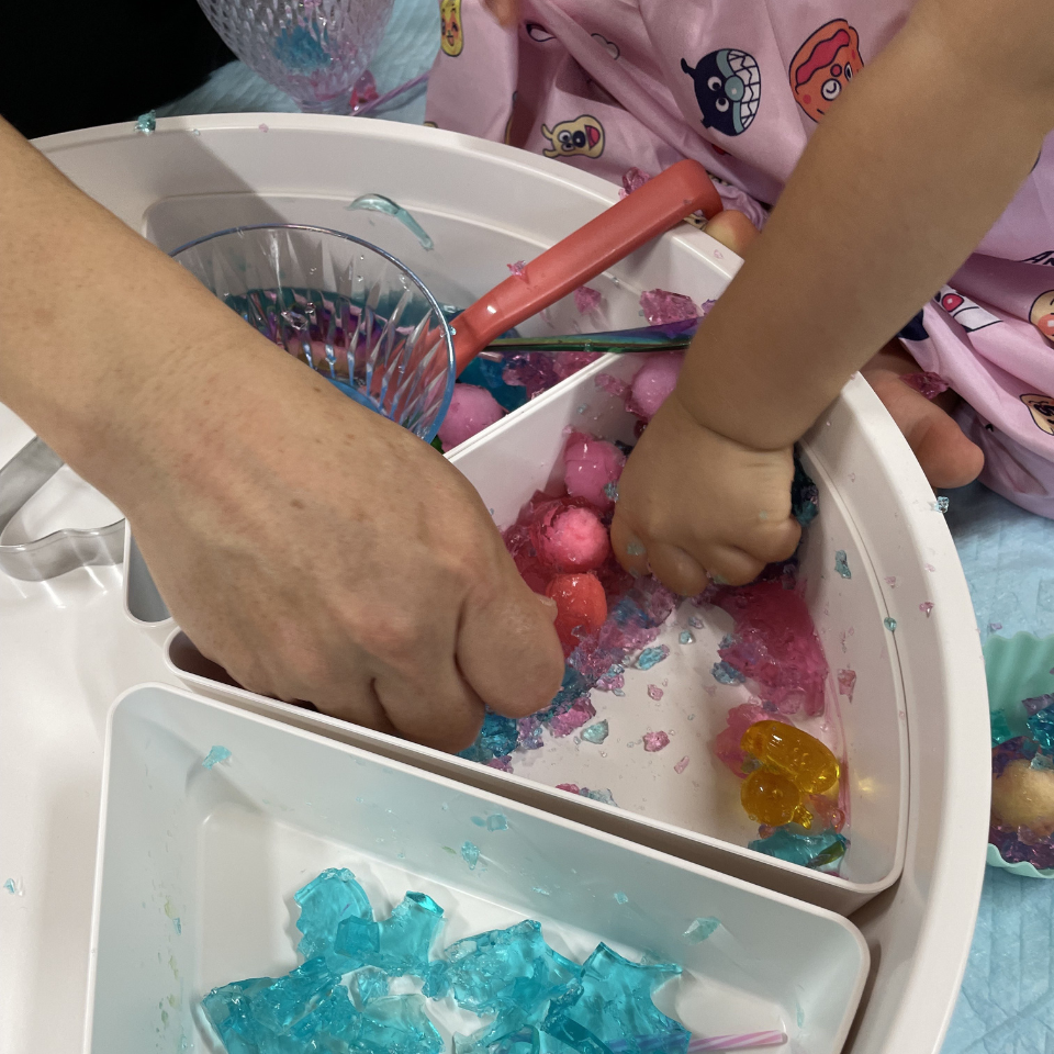 色とりどりのジェル素材を親子で触って遊ぶセンサリープレイの様子