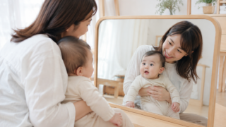 赤ちゃんを抱っこして鏡を一緒に見るママ