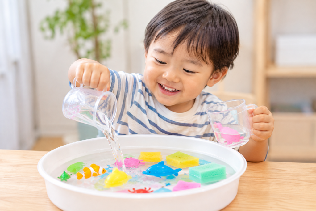水を入れたトレイで水あそびをする子ども