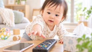 赤ちゃんがリモコンやスマホなど身近なものに手を伸ばしている様子